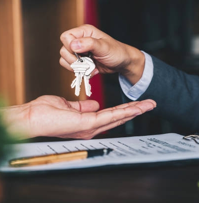 estate agent giving house keys to woman and sign agreement in office
